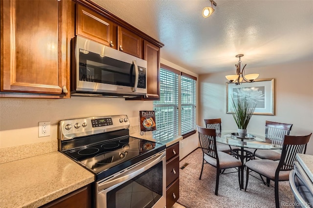 2090 S Hannibal Way Unit F, Aurora, CO 80013 - kitchen featuring a textured ceiling, hanging light fixtures, light countertops, an inviting chandelier, and stainless steel appliances