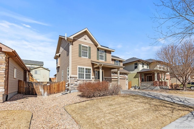 view of front of home with a garage, stone siding, driveway, and fence