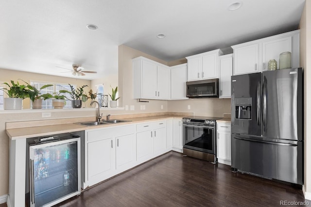 kitchen with beverage cooler, a sink, light countertops, appliances with stainless steel finishes, and dark wood-style floors