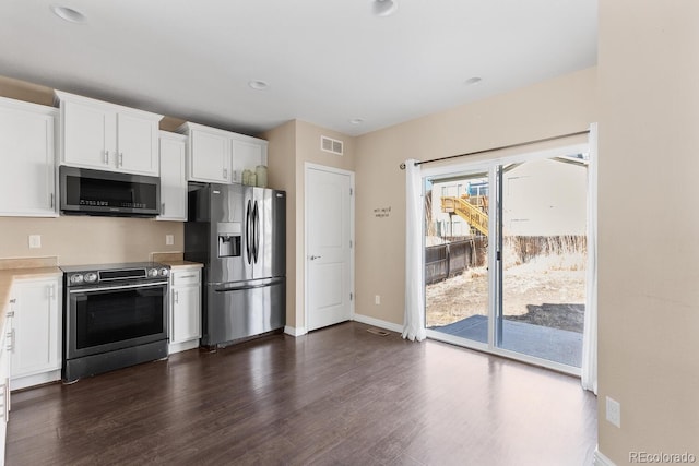 kitchen featuring visible vents, white cabinets, dark wood-style flooring, stainless steel appliances, and light countertops