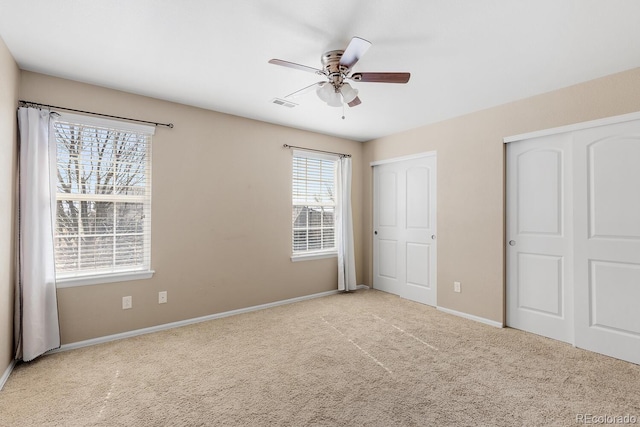 unfurnished bedroom featuring carpet, visible vents, ceiling fan, and baseboards