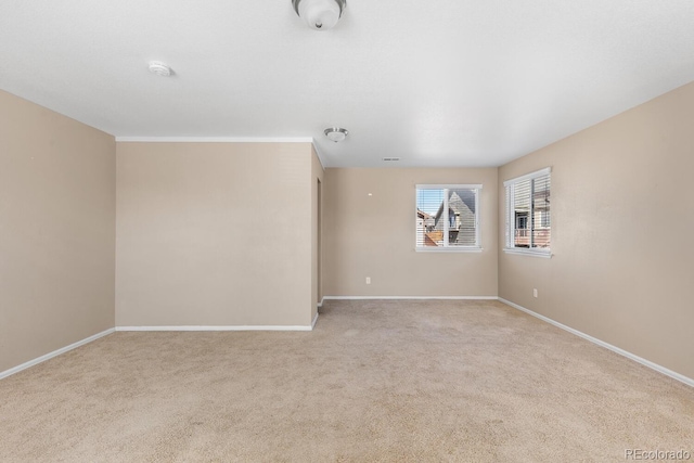 unfurnished room with baseboards and light colored carpet