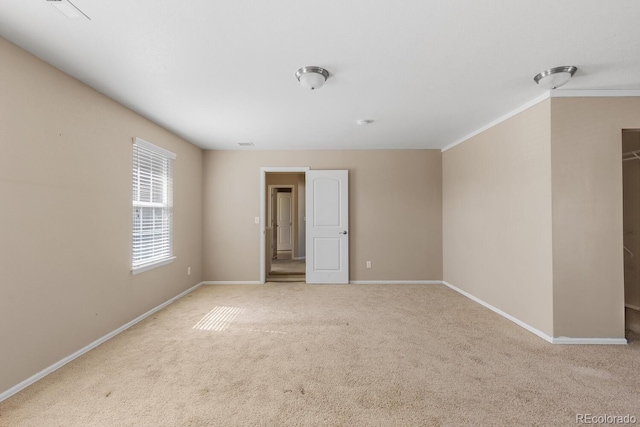 carpeted spare room featuring ornamental molding, visible vents, and baseboards