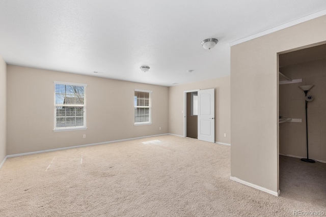 unfurnished bedroom with carpet floors, baseboards, a walk in closet, and a closet