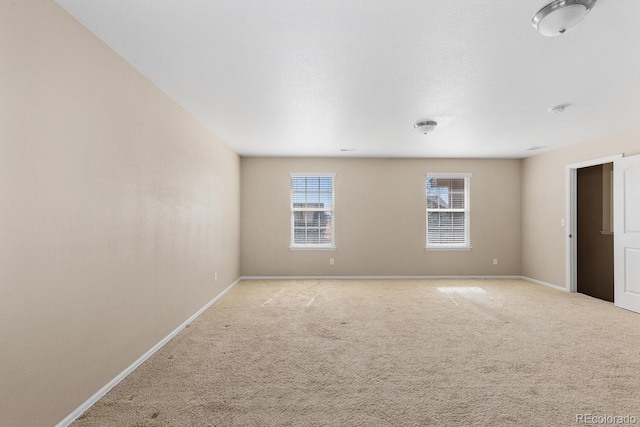 unfurnished room featuring light carpet and baseboards