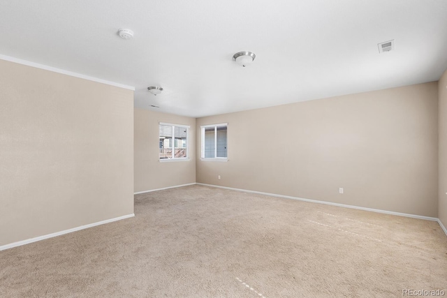 spare room featuring light carpet, visible vents, and baseboards