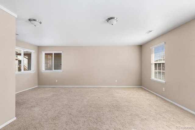 carpeted spare room featuring visible vents and baseboards