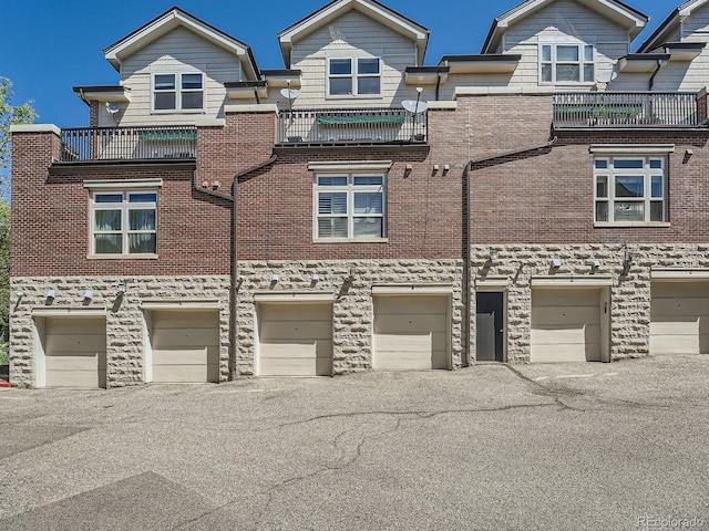 30 Garfield St Unit B, Denver, CO 80206 - view of front facade with a garage, stone siding, driveway, a balcony, and brick siding