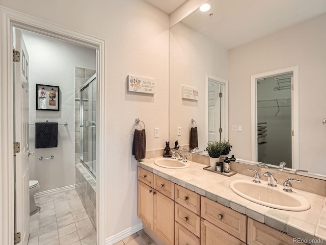 30 Garfield St Unit B, Denver, CO 80206 - full bathroom featuring toilet, double vanity, combined bath / shower with glass door, tile patterned floors, and a walk in closet