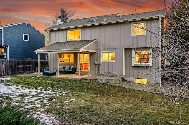 back house at dusk with outdoor lounge area, a patio area, and a yard