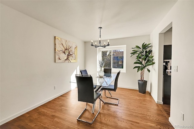 dining space with hardwood / wood-style flooring and an inviting chandelier