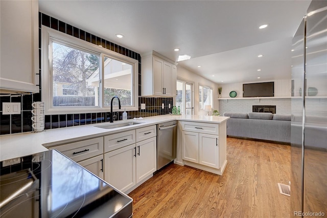 kitchen featuring dishwasher, kitchen peninsula, sink, and a wealth of natural light