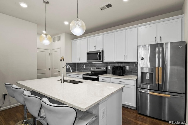 kitchen with a center island with sink, white cabinetry, sink, appliances with stainless steel finishes, and pendant lighting