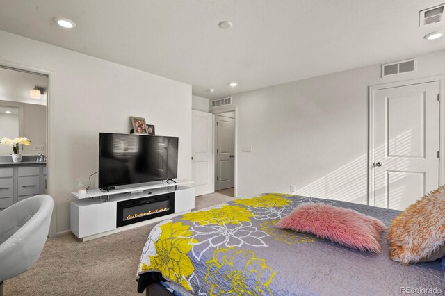 bedroom featuring ensuite bathroom and light colored carpet