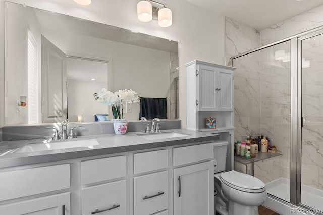 bathroom with toilet, vanity, and a shower with door