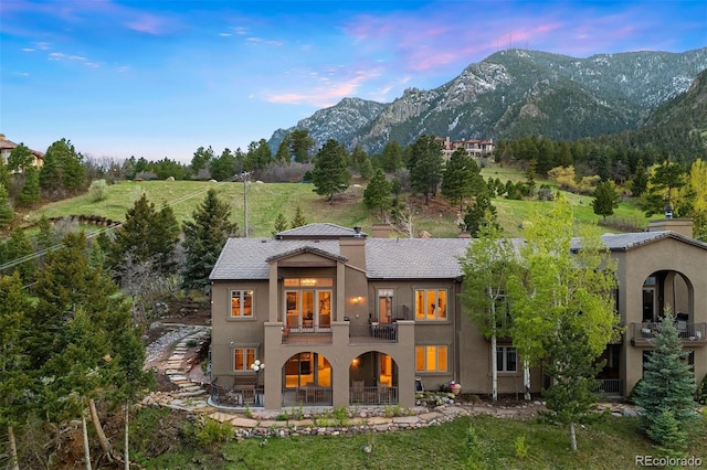 948 Manor Gate Pt, Colorado Springs, CO 80906 - back of house at dusk featuring a balcony, stucco siding, a patio area, and a mountain view