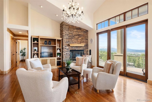 948 Manor Gate Pt, Colorado Springs, CO 80906 - living room featuring high vaulted ceiling, a chandelier, a stone fireplace, wood finished floors, and baseboards