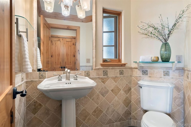 948 Manor Gate Pt, Colorado Springs, CO 80906 - bathroom featuring tile walls, a wainscoted wall, toilet, and a chandelier