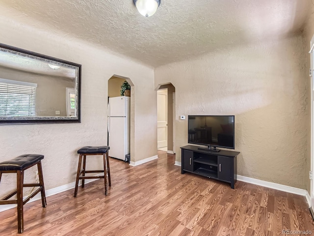 3265 S Ogden St, Englewood, CO 80113 - living area with arched walkways, a textured ceiling, a textured wall, wood finished floors, and baseboards