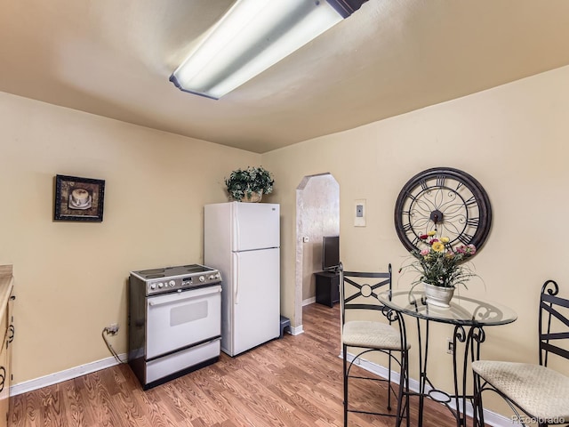 3265 S Ogden St, Englewood, CO 80113 - kitchen with electric range oven, freestanding refrigerator, arched walkways, and light wood-style floors