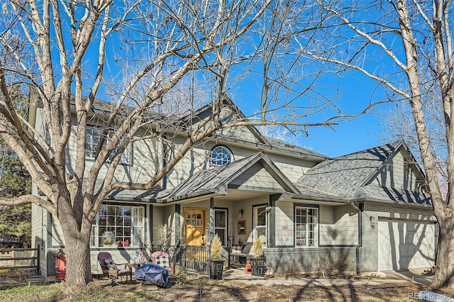 view of front facade featuring a garage, covered porch, brick siding, fence, and roof with shingles