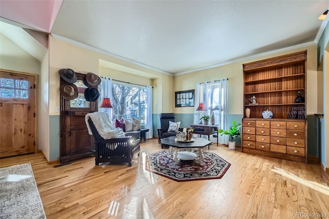 sitting room with ornamental molding and light hardwood / wood-style floors