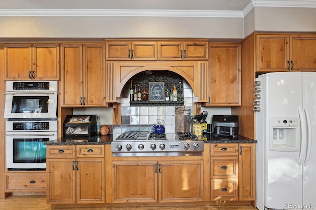 kitchen featuring white fridge with ice dispenser, brown cabinetry, stainless steel gas stovetop, and multiple ovens