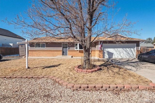 single story home with concrete driveway, brick siding, an attached garage, and fence