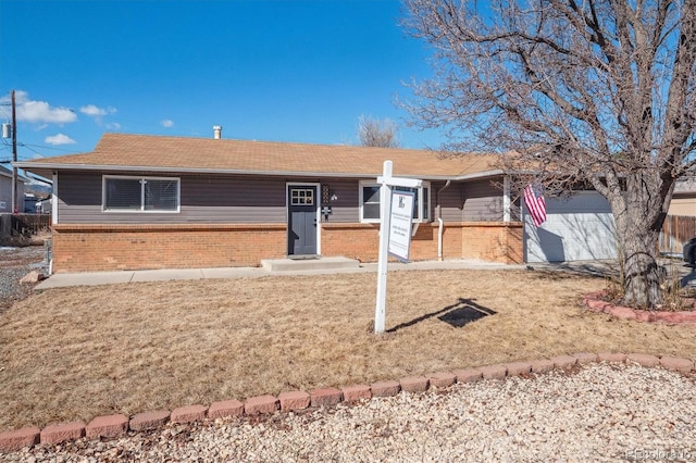 ranch-style house with a front yard, brick siding, and an attached garage