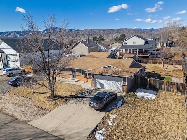 ranch-style house featuring a garage, concrete driveway, a residential view, fence, and a mountain view