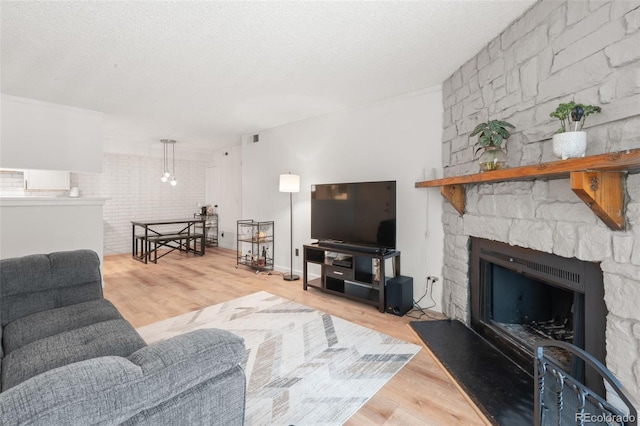 living room featuring a fireplace, a textured ceiling, and light wood-type flooring