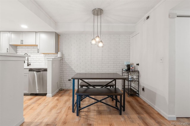 dining area with crown molding, brick wall, and light hardwood / wood-style flooring