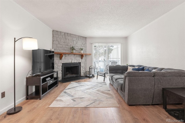 living room with wood-type flooring, ornamental molding, a textured ceiling, and a fireplace