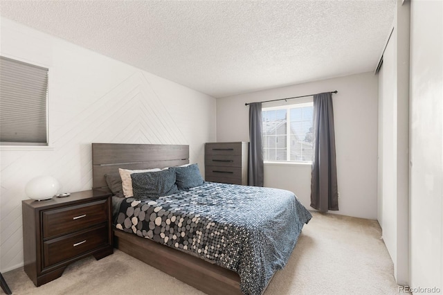 bedroom featuring light colored carpet and a textured ceiling