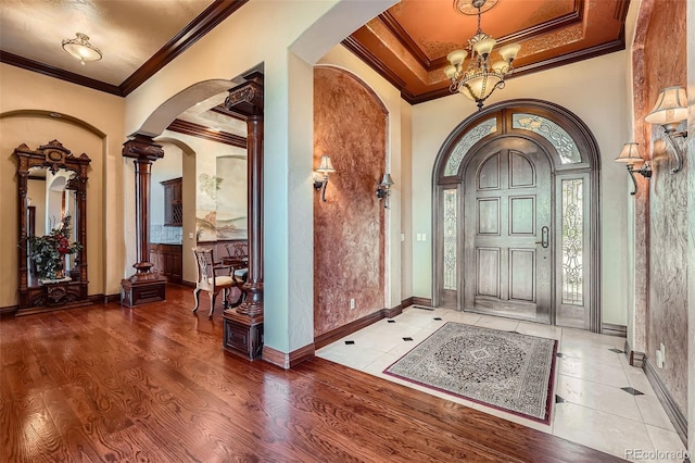 4725 Palmer Ridge Dr, Parker, CO 80134 - entrance foyer featuring arched walkways, a chandelier, crown molding, wood finished floors, and decorative columns
