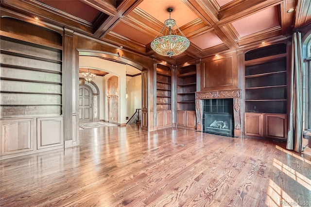 4725 Palmer Ridge Dr, Parker, CO 80134 - unfurnished living room featuring built in features, arched walkways, a tiled fireplace, crown molding, and coffered ceiling