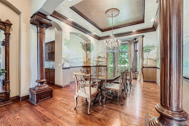 4725 Palmer Ridge Dr, Parker, CO 80134 - dining area with ornamental molding, a chandelier, wood finished floors, a raised ceiling, and decorative columns
