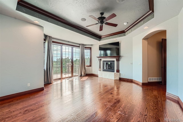 4725 Palmer Ridge Dr, Parker, CO 80134 - unfurnished living room featuring a raised ceiling, crown molding, a ceiling fan, arched walkways, and wood finished floors