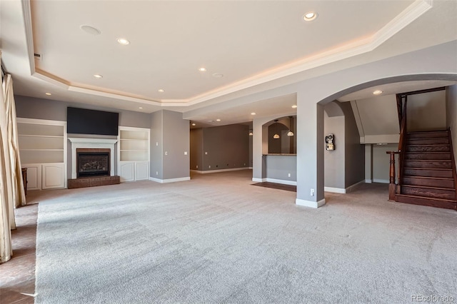 4725 Palmer Ridge Dr, Parker, CO 80134 - unfurnished living room featuring a raised ceiling, light colored carpet, recessed lighting, arched walkways, and a fireplace with raised hearth