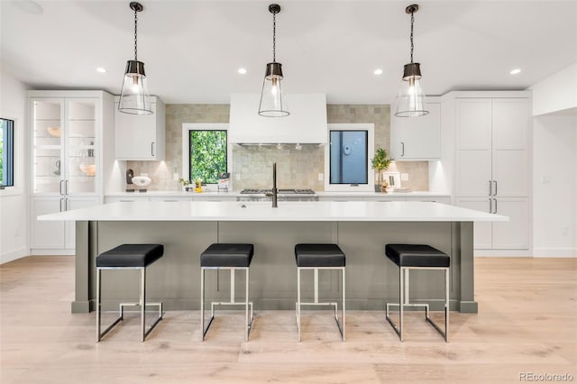 kitchen featuring white cabinets, light countertops, a large island with sink, and a kitchen breakfast bar