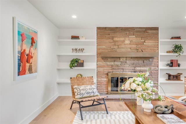 sitting room with built in shelves, a fireplace, recessed lighting, light wood-type flooring, and baseboards