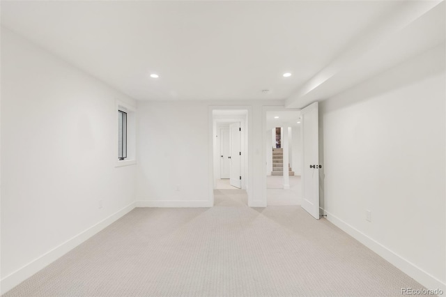 spare room featuring recessed lighting, light colored carpet, and baseboards