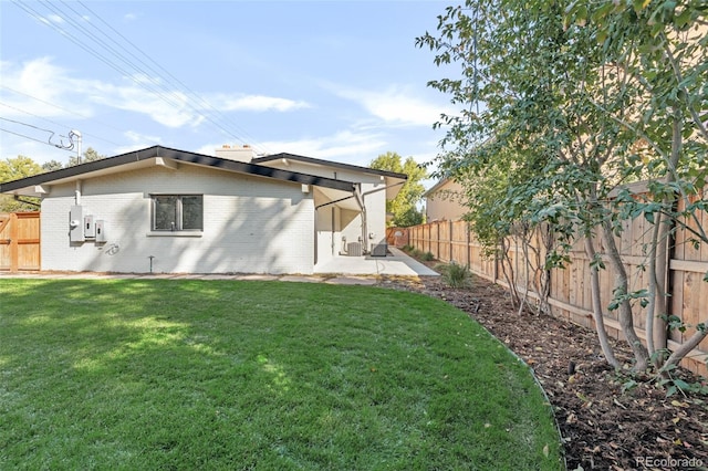 rear view of property with a patio area, a fenced backyard, a lawn, and brick siding