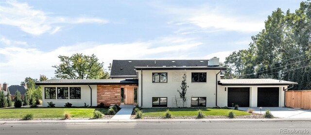 tri-level home with a garage, concrete driveway, fence, and a front lawn