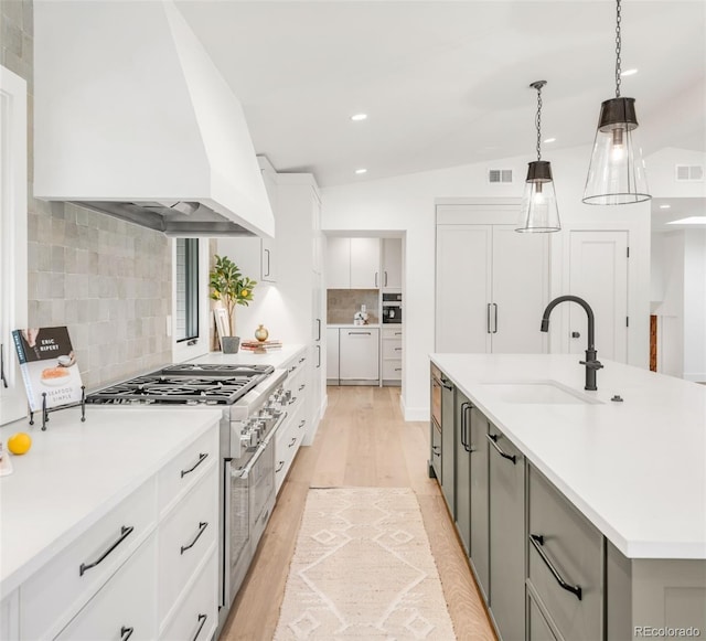 kitchen with premium range hood, a sink, white cabinetry, light countertops, and a large island