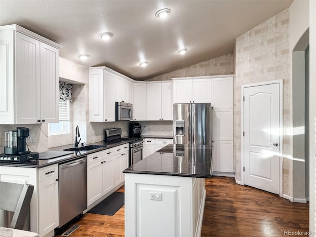 kitchen with lofted ceiling, a sink, dark wood-type flooring, appliances with stainless steel finishes, and white cabinetry