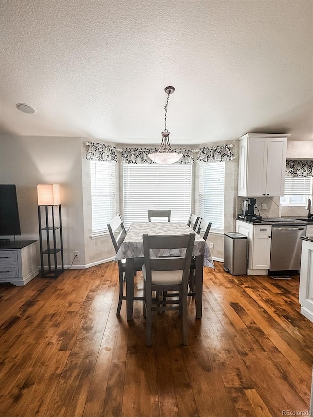 dining area with a healthy amount of sunlight, a textured ceiling, baseboards, and dark wood-style flooring