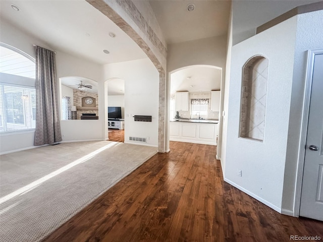 unfurnished living room with visible vents, dark wood-type flooring, baseboards, a ceiling fan, and a sink