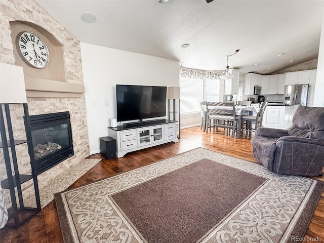 living area with a fireplace, a textured ceiling, dark wood-type flooring, and lofted ceiling