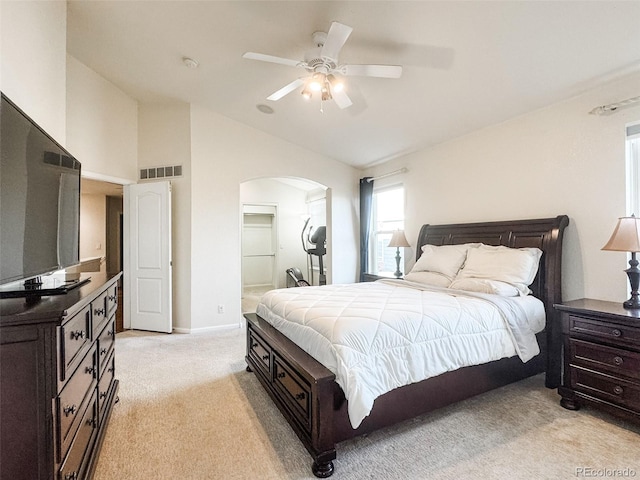 bedroom with a ceiling fan, visible vents, arched walkways, vaulted ceiling, and light carpet